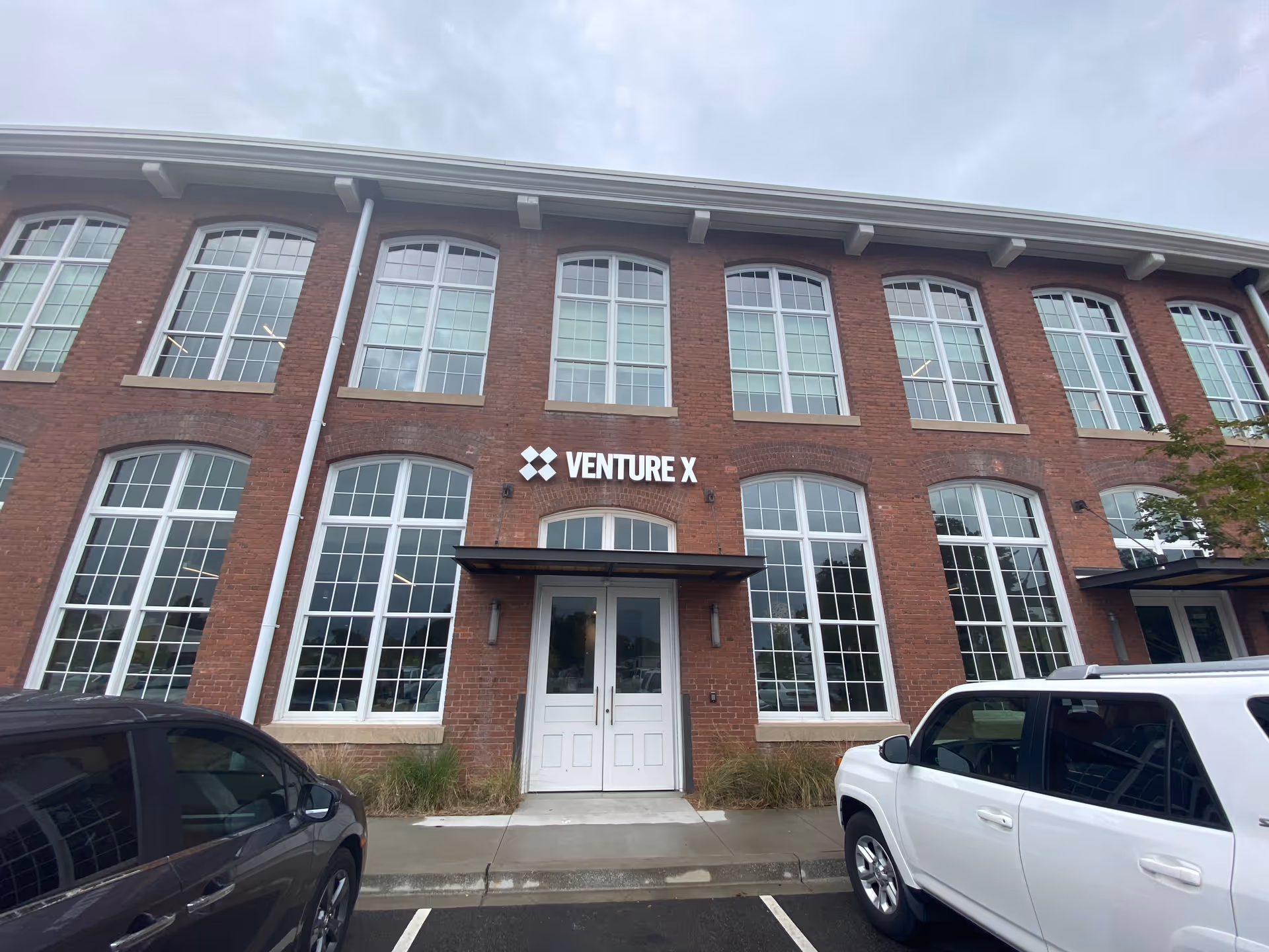 Brick building facade with tall arched windows and Venture X sign above entrance.