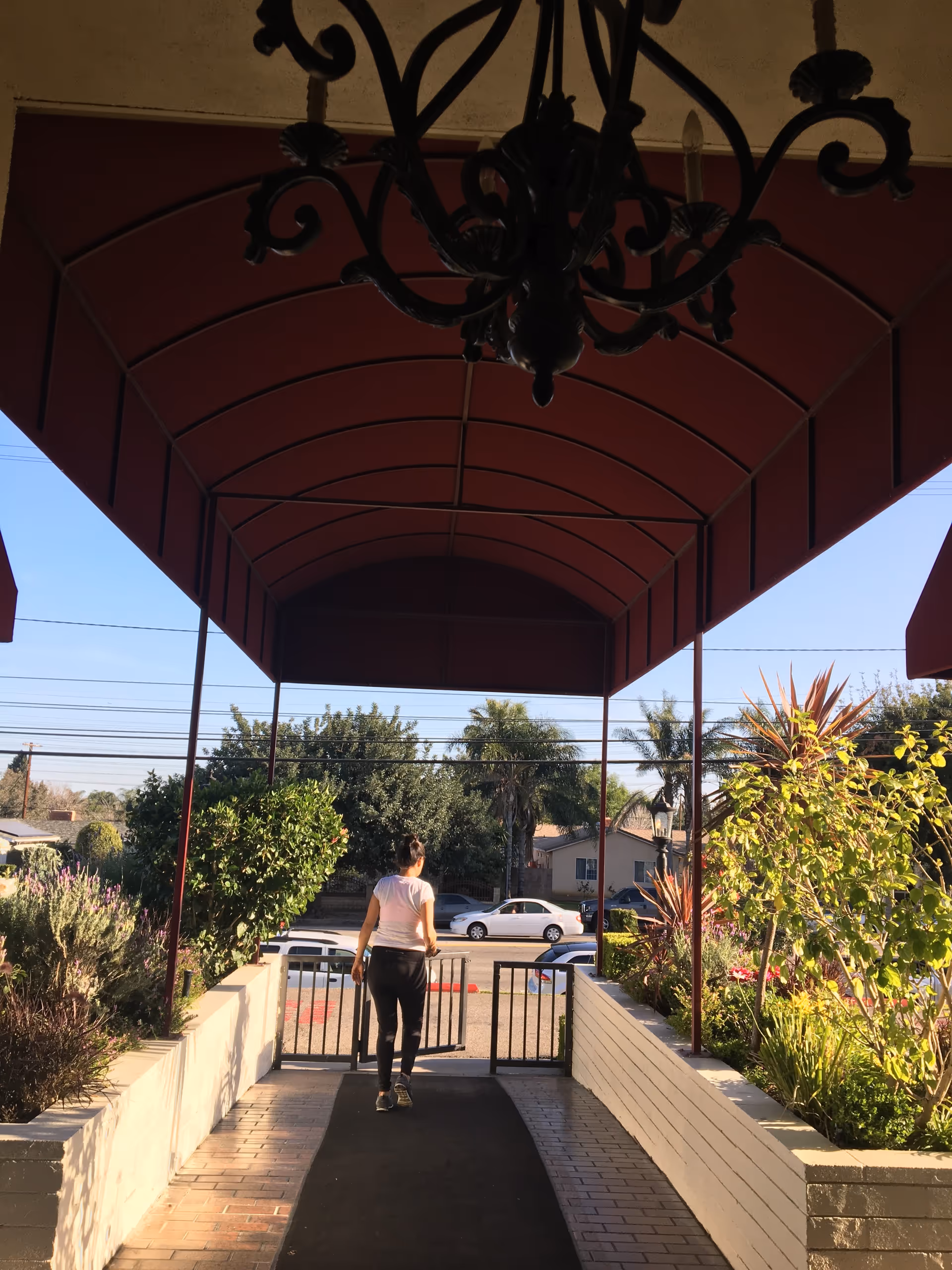 Outdoor covered entrance of Rinaldi Convalescent Hospital, with a person walking toward a gate.