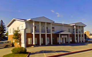 Exterior view of a two-story senior living facility with brick base and columns.