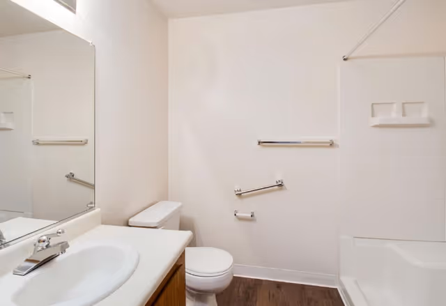 Bathroom featuring a sink, toilet, bathtub, and wall grab bars.