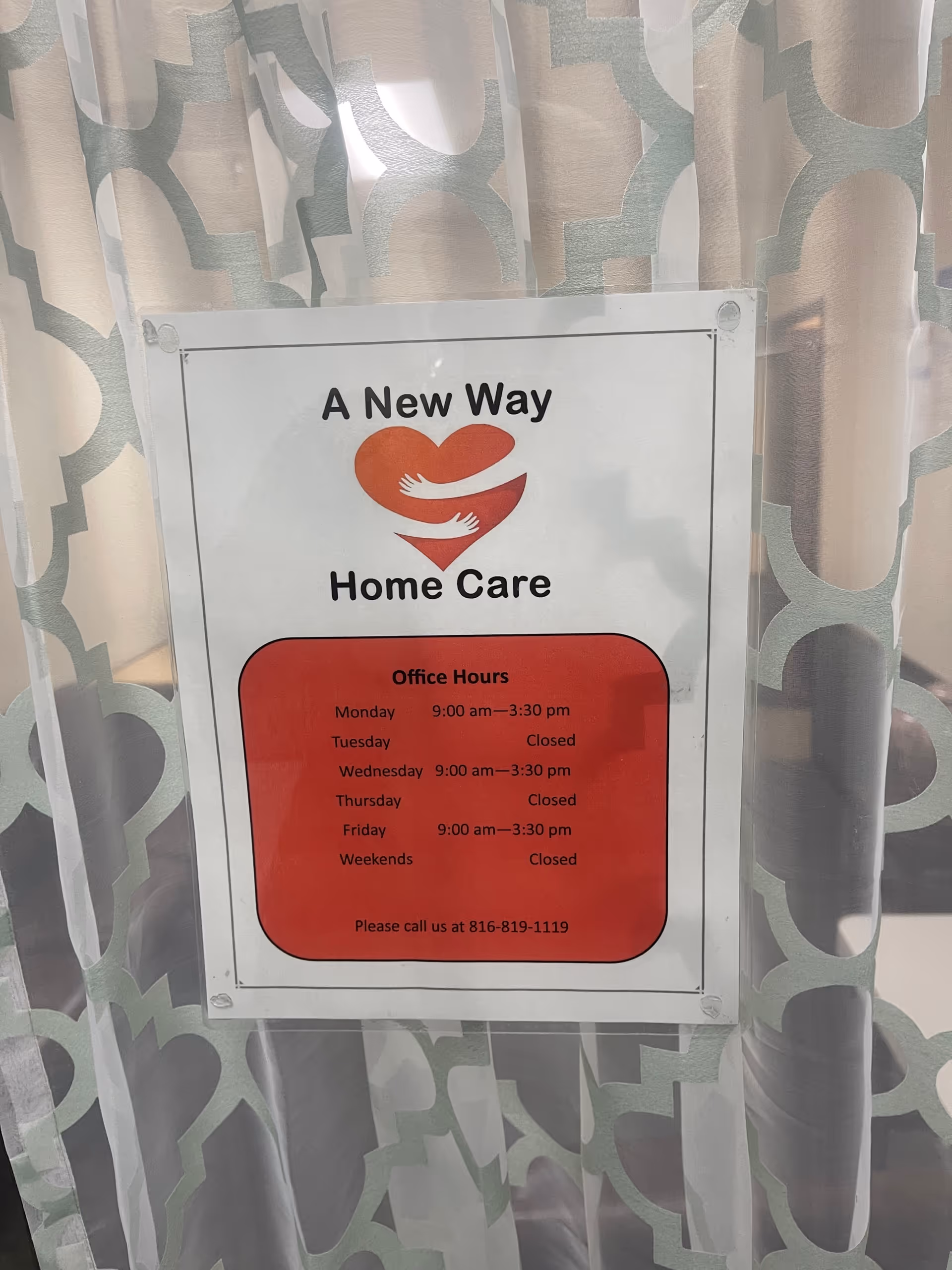 Sign reads 'A New Way Home Care' with office hours on patterned curtains.