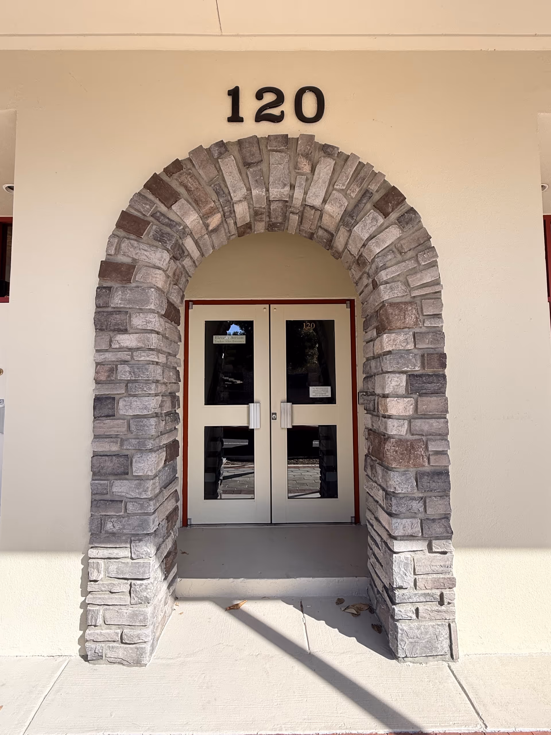Exterior entrance with stone archway and double glass doors labeled 120.