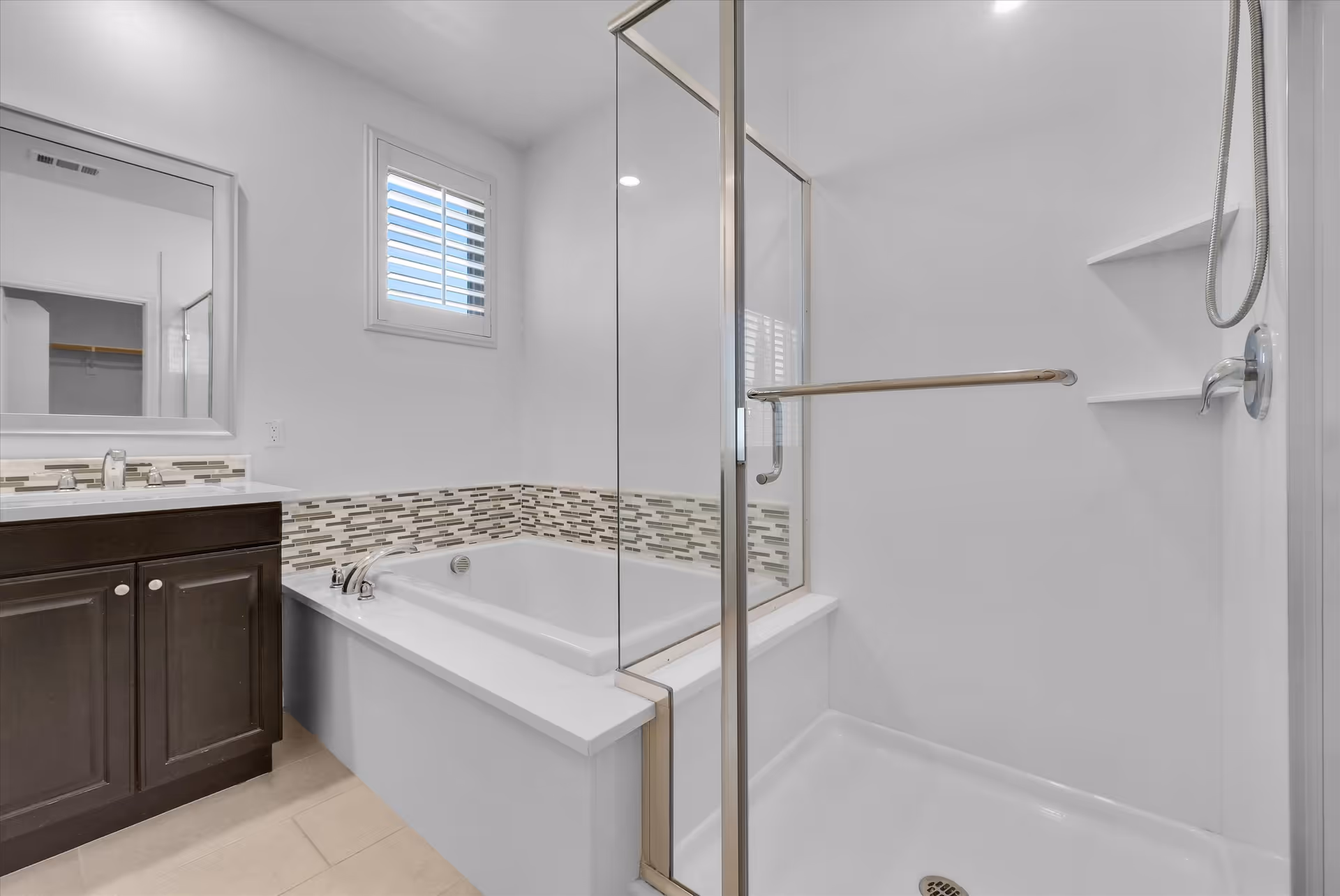 Modern bathroom with glass shower, soaking tub, and dark vanity.