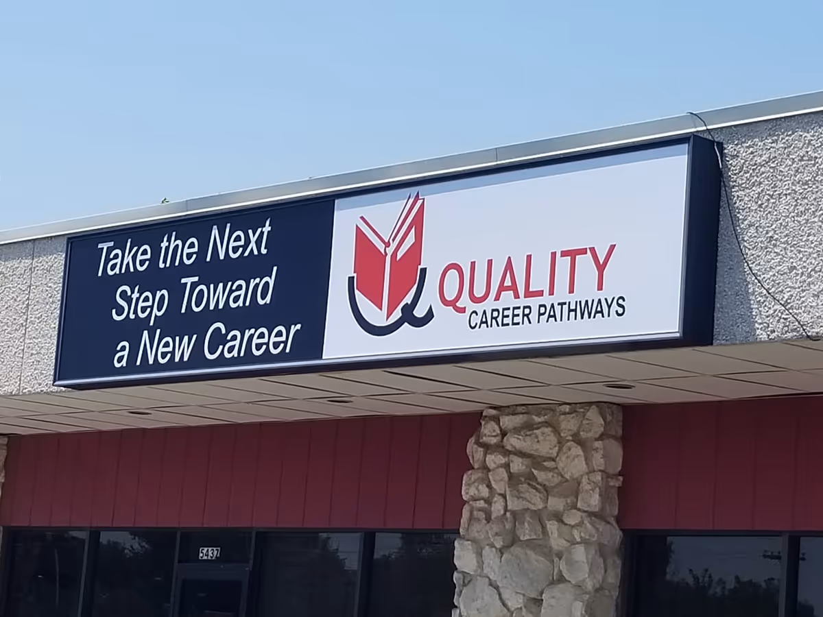 Exterior storefront with a large sign reading Quality Career Pathways beside a stone column