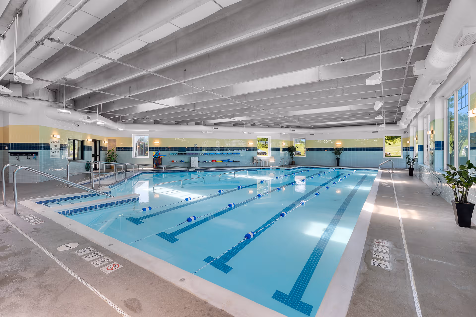 Indoor swimming pool with lane dividers, tiled walls, and bright windows.