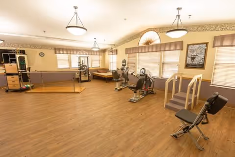 Bright indoor exercise room in a senior living facility with cardio equipment.