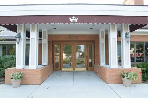Front entrance of Kingston Residence of Marion with brick columns and maroon canopy.