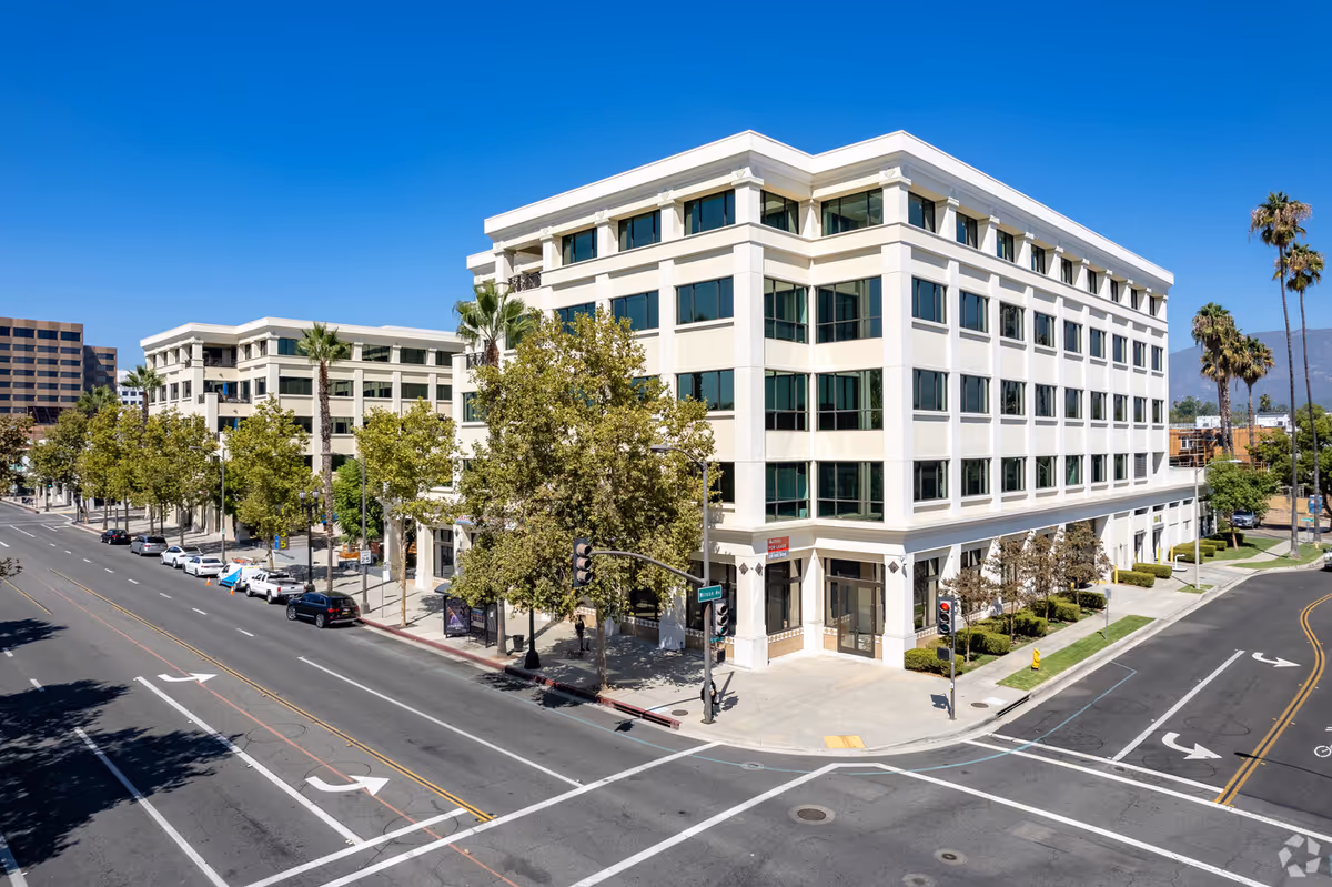 Exterior view of a multi-story white building at a street corner with palm trees