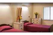 Two twin beds with pink comforters and matching dressers in a bright shared bedroom.
