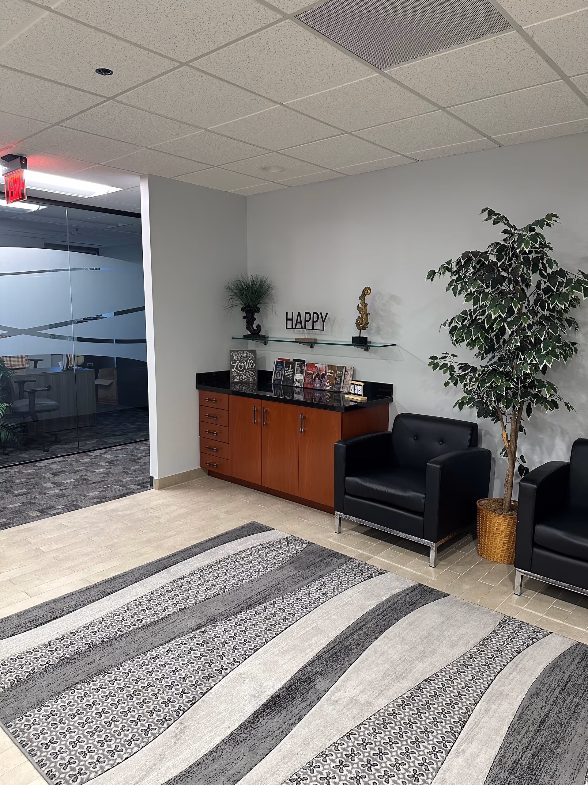 Lobby seating area with a plant, cabinet, and 'HAPPY' decor.