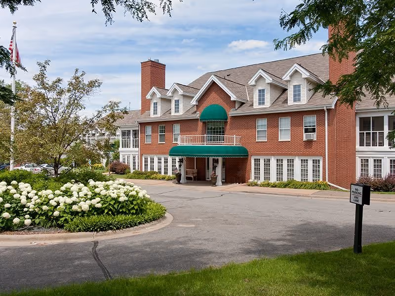 Exterior view of Meridian Manor senior living building with brick facade, green awnings, and landscaping.