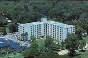 Aerial view of Hugh Ash Manor, a multi-story senior living building surrounded by trees.