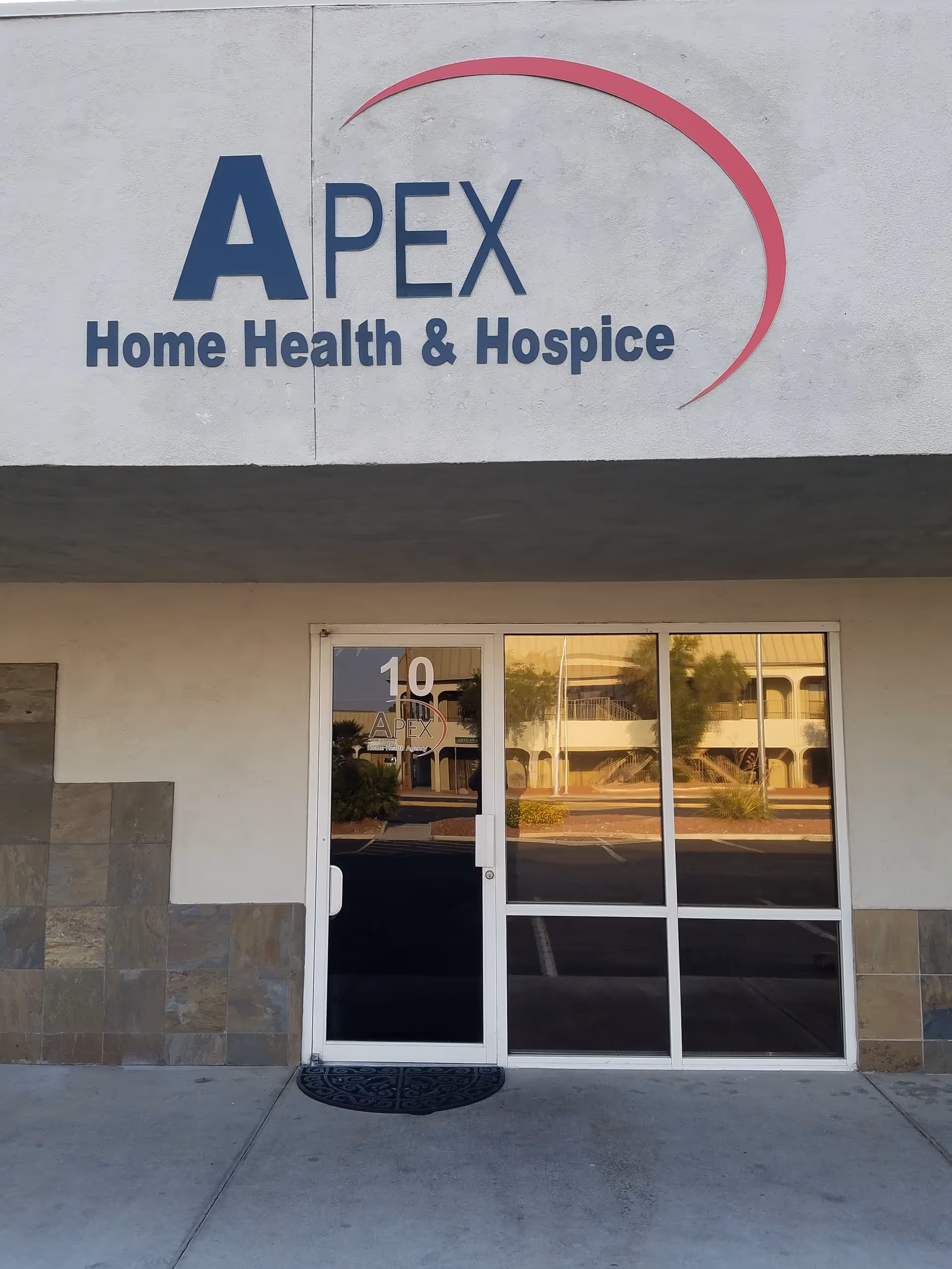 The storefront entrance of Apex Home Health & Hospice with glass doors and sign.