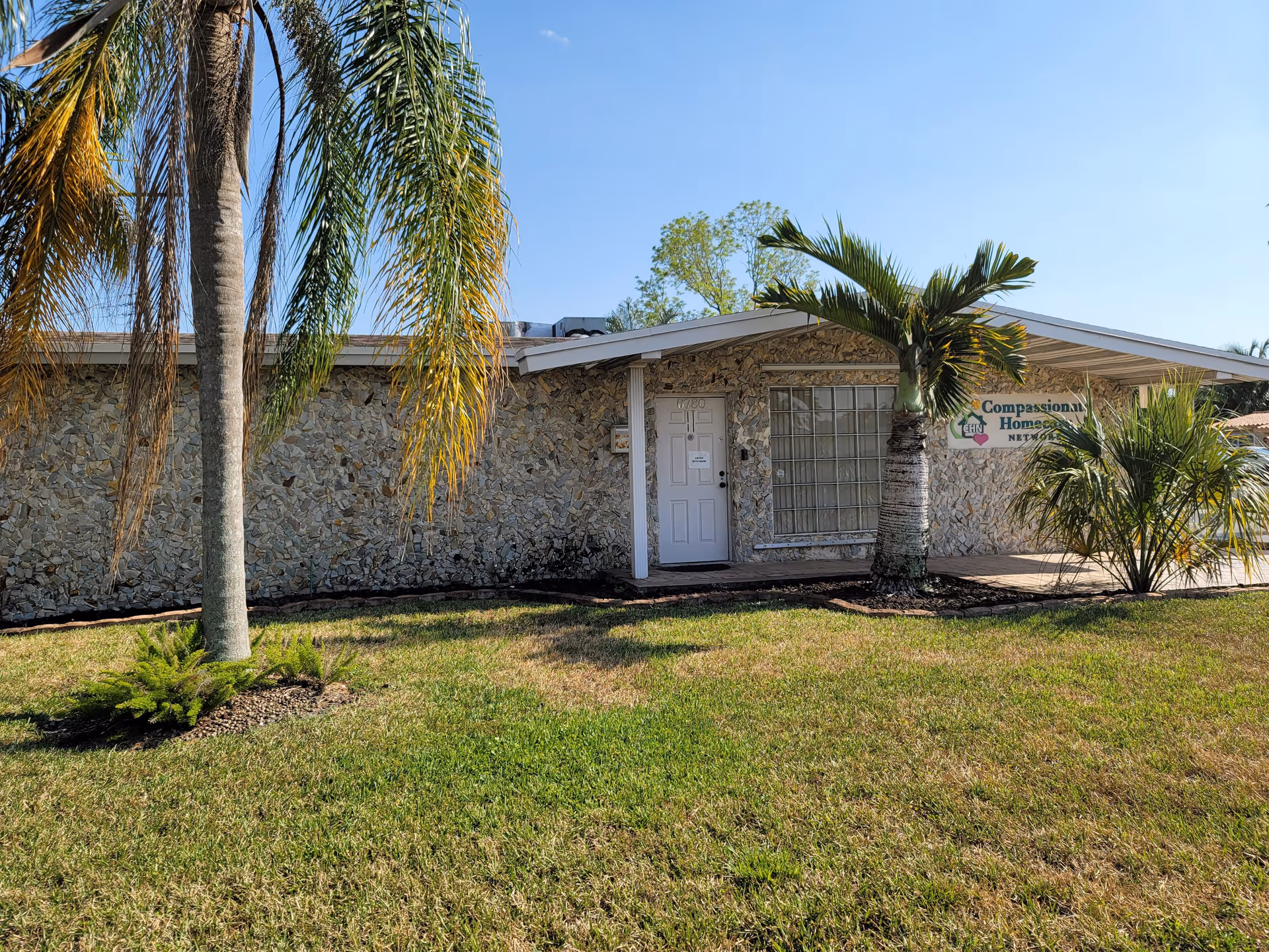 Exterior view of Compassionate Homecare Network building with palm trees and a grassy front yard.