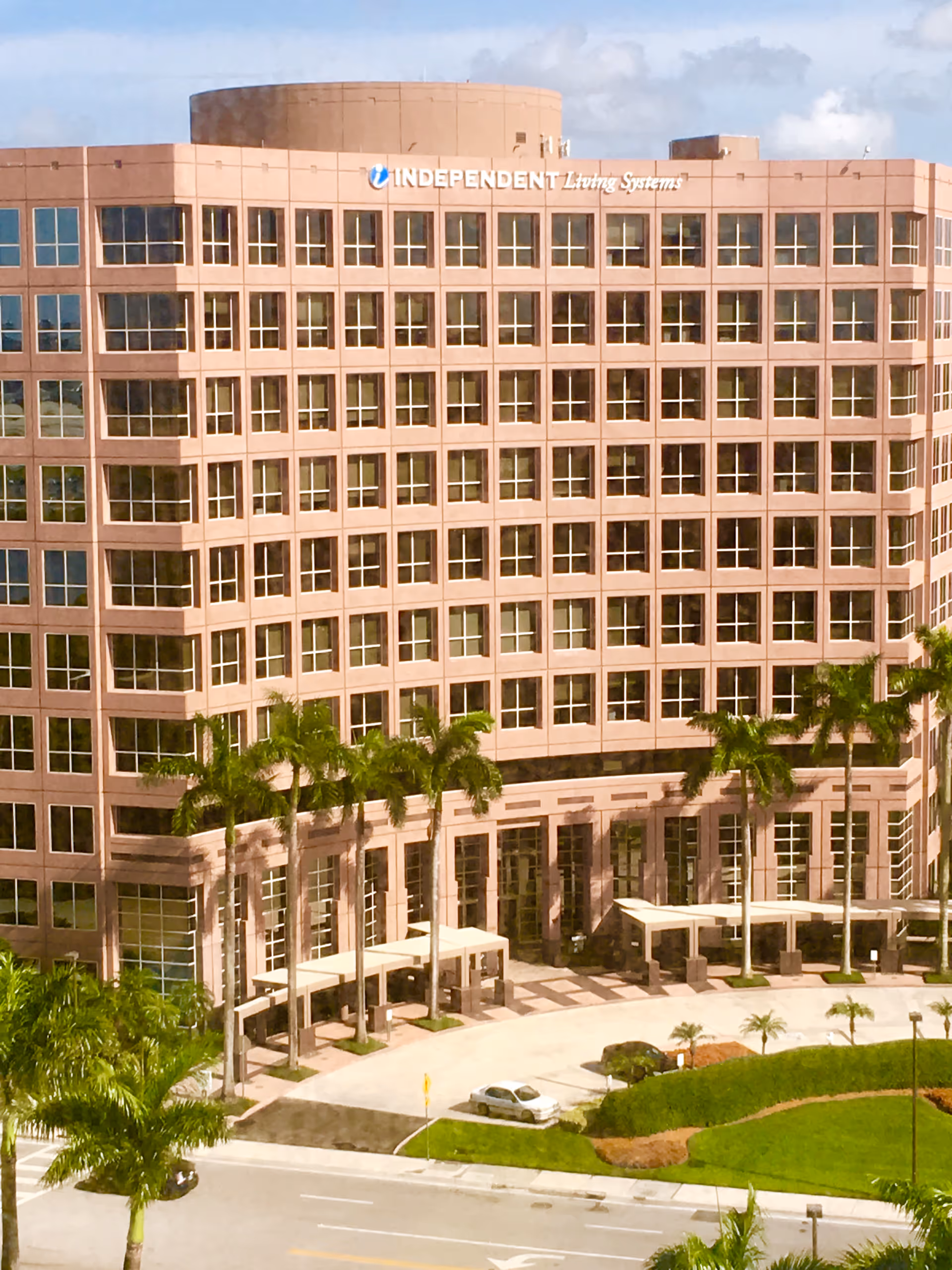 Exterior view of a pink multi-story building labeled Independent Living Systems with palm trees.