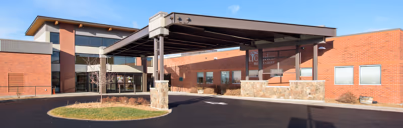 A brick senior living facility exterior with a covered entrance and driveway.
