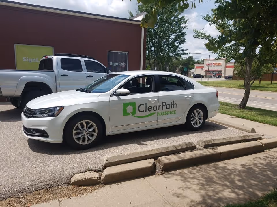 White sedan with ClearPath Hospice branding parked in a lot outside a building.