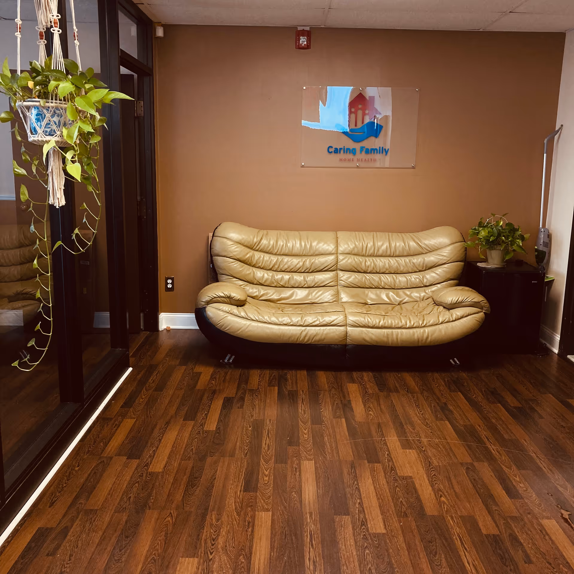 Beige leather sofa against brown wall with Caring Family Home Health sign.