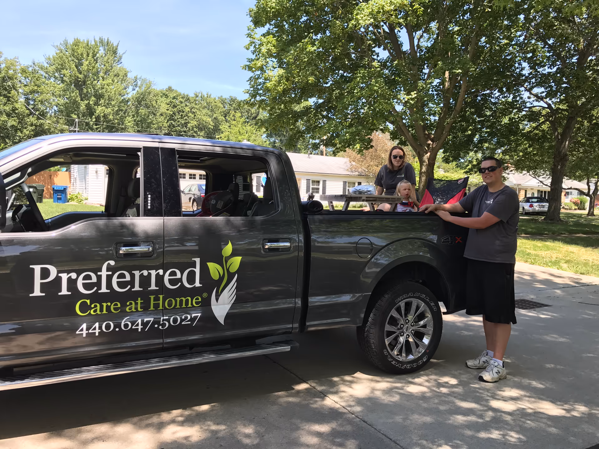 Outdoor scene with a branded truck displaying Preferred Care at Home logo and people nearby.