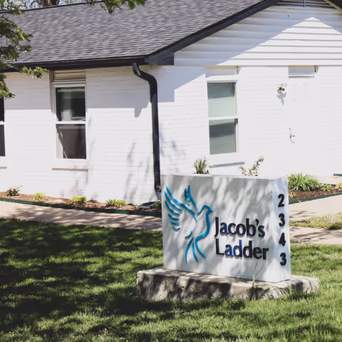 Exterior of a white brick building with a front sign reading Jacob's Ladder.