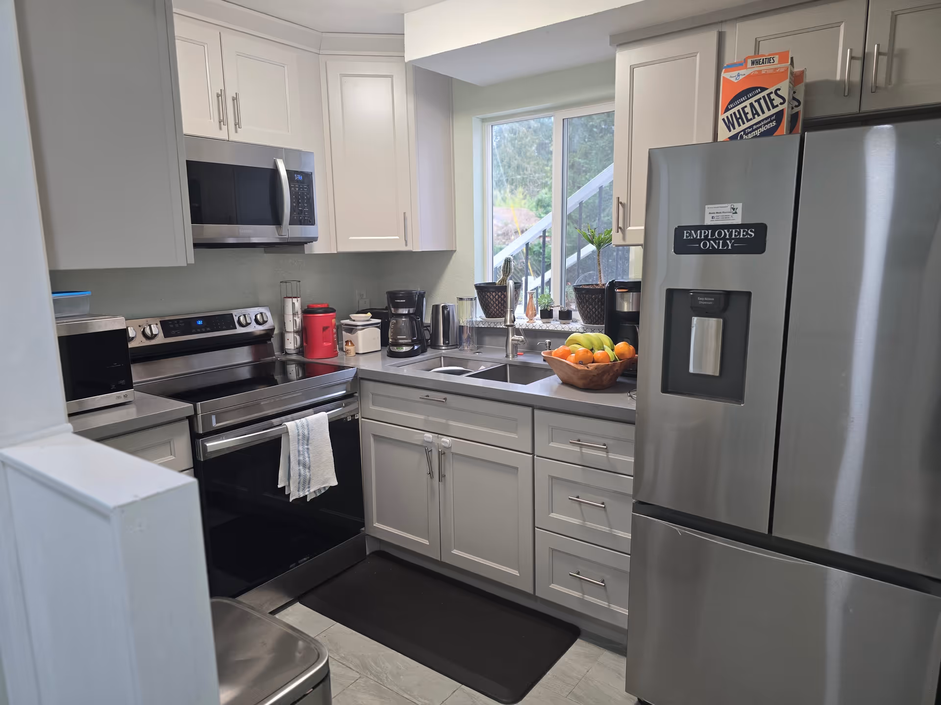 Modern kitchen with stainless appliances, white cabinets, and a fruit bowl on the counter.