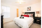 A neatly made bedroom featuring a large bed, two nightstands, lamps, and a ceiling fan.
