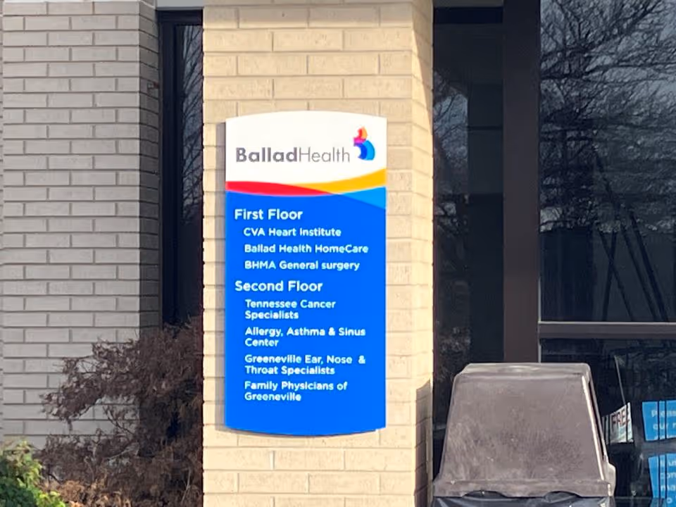 Exterior brick building with Ballad Health sign and blue service directory panel.