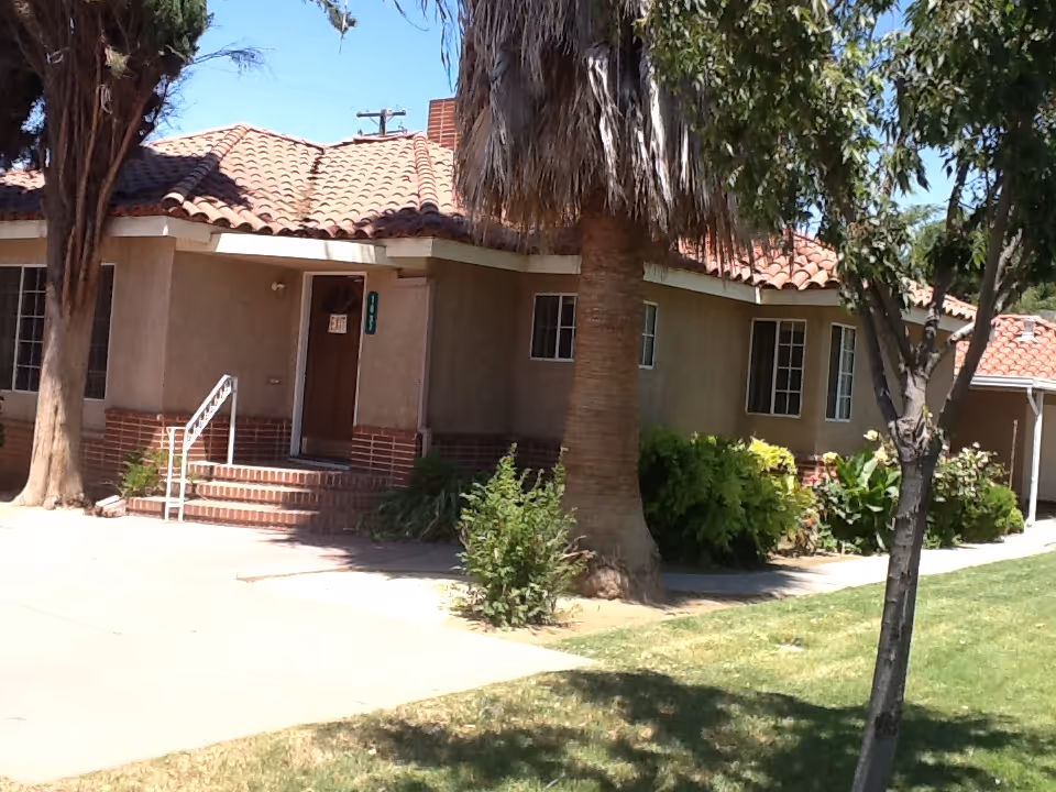 Exterior view of a single-story senior living facility with tiled roof and entrance stairs.
