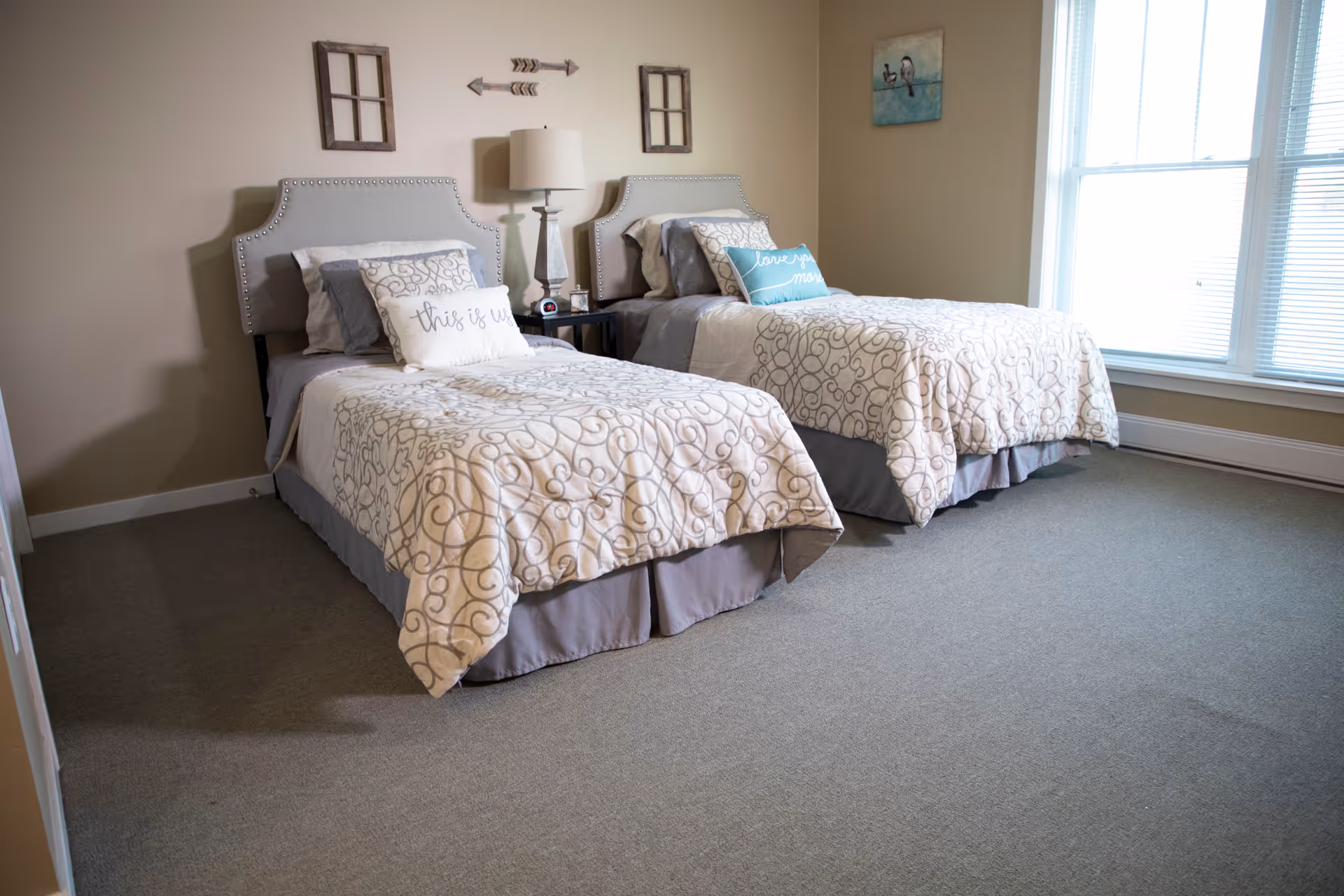 Two twin beds with matching quilted bedspreads in a bright neutral bedroom.