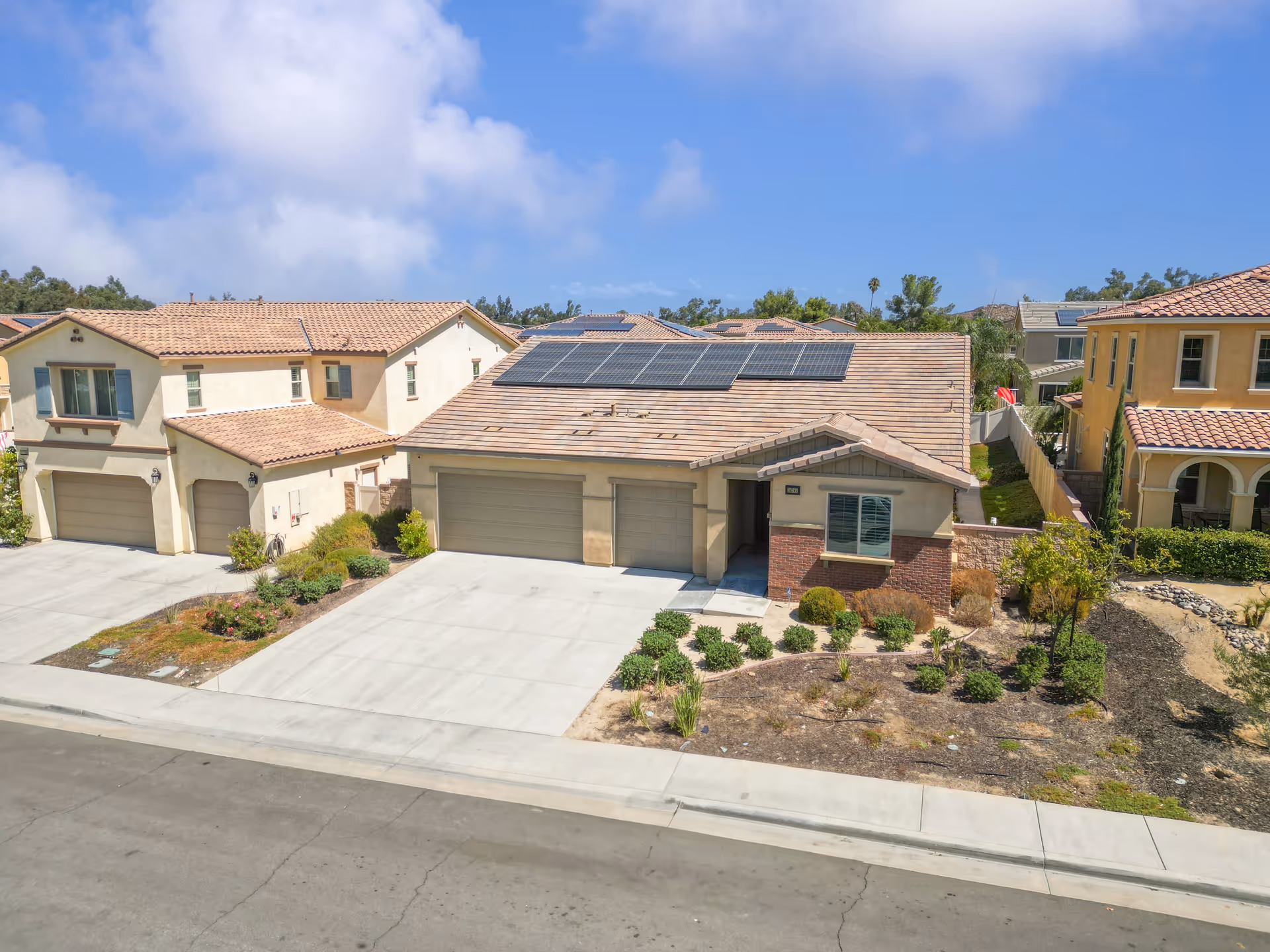 Exterior view of a residential assisted living-style building with multiple garages and desert landscaping.