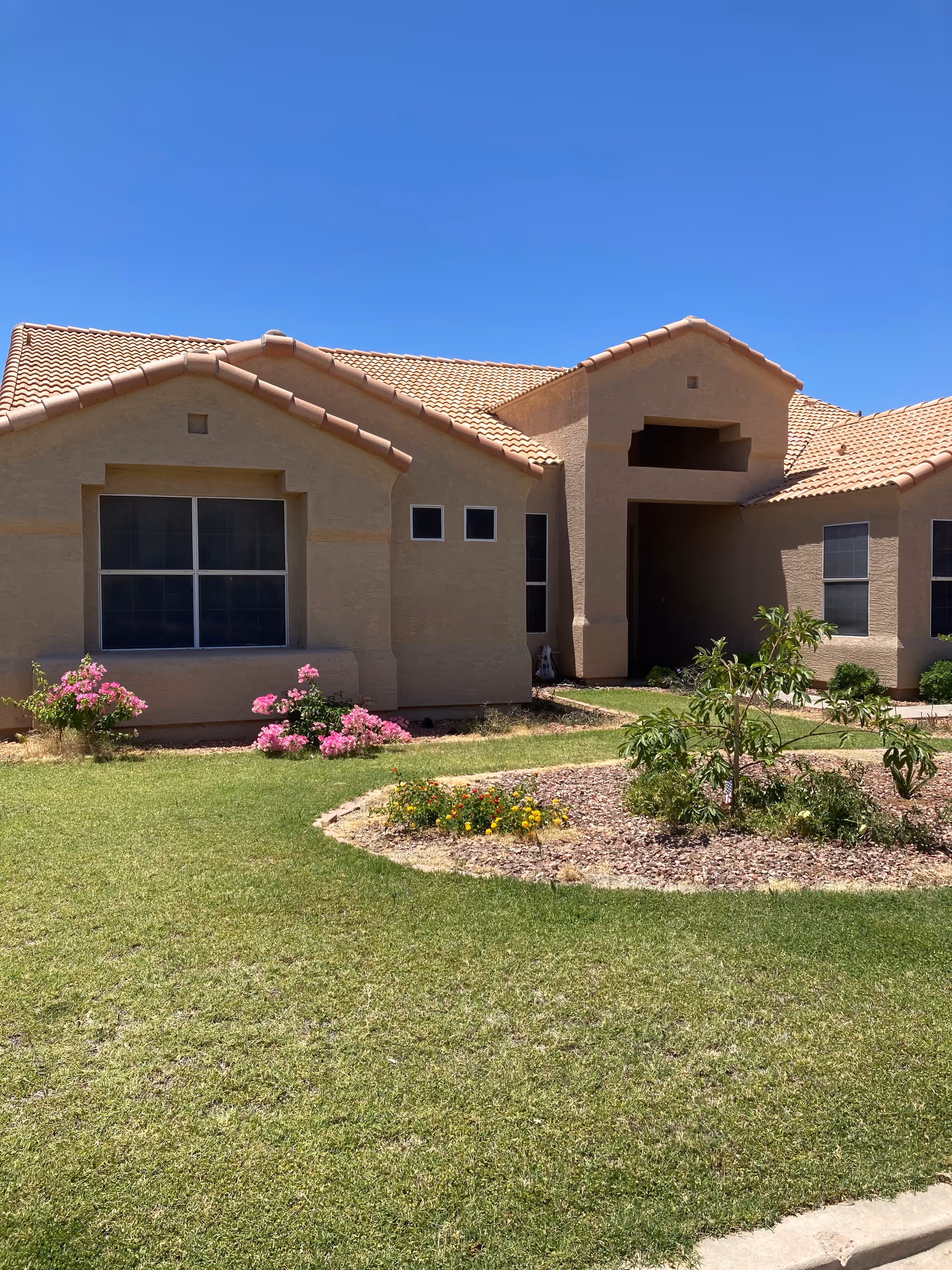 Exterior view of a tan stucco senior living facility with a tiled roof and landscaping.