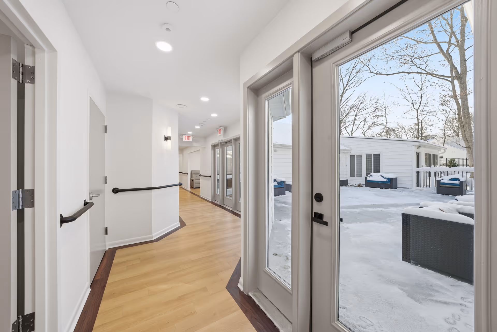 Interior hallway at Havenwood Homes at Kresson with glass doors opening to snowy outdoor seating