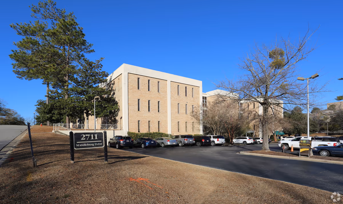 Exterior view of Luxe Home Care facility with brick building, parking lot, and sign.