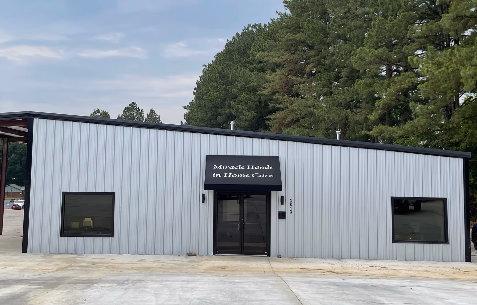 Gray metal building with glass doors and an awning sign reading Miracle Hands in Home Care.