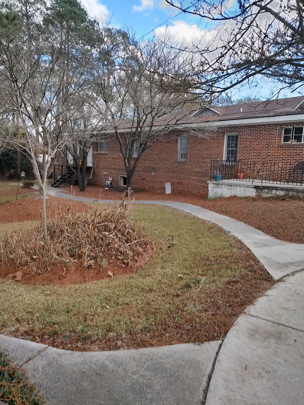 Brick exterior of a senior living facility with a curved walkway and bare trees.
