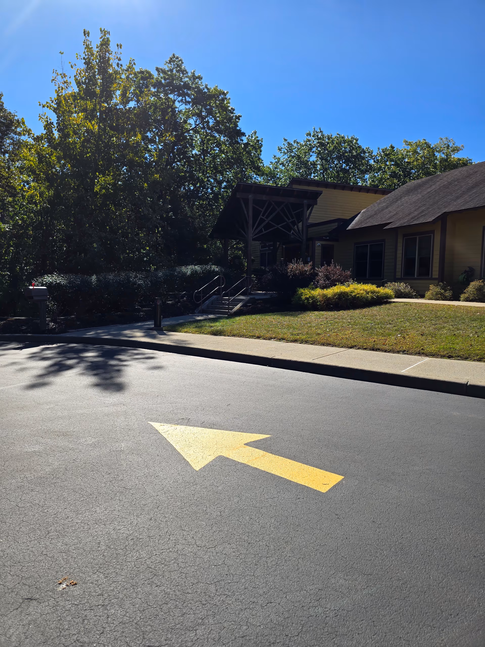 Exterior view of Mountain Valley Hospice entrance with a paved road and arrow sign