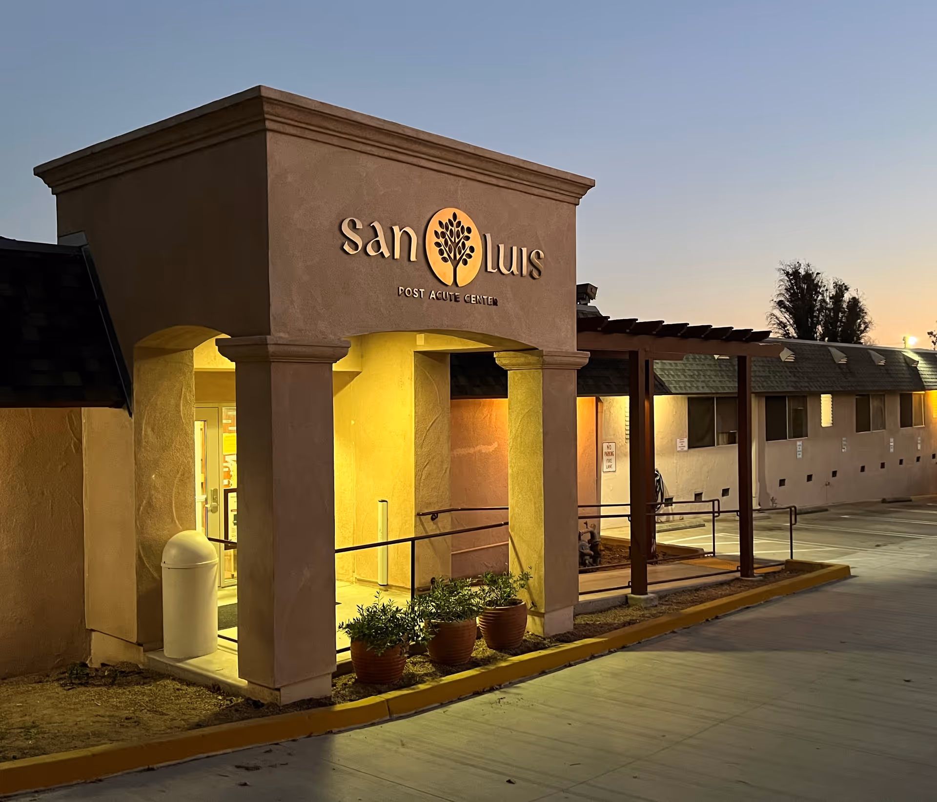 Exterior view of a senior care center entrance with columns and warm lighting.