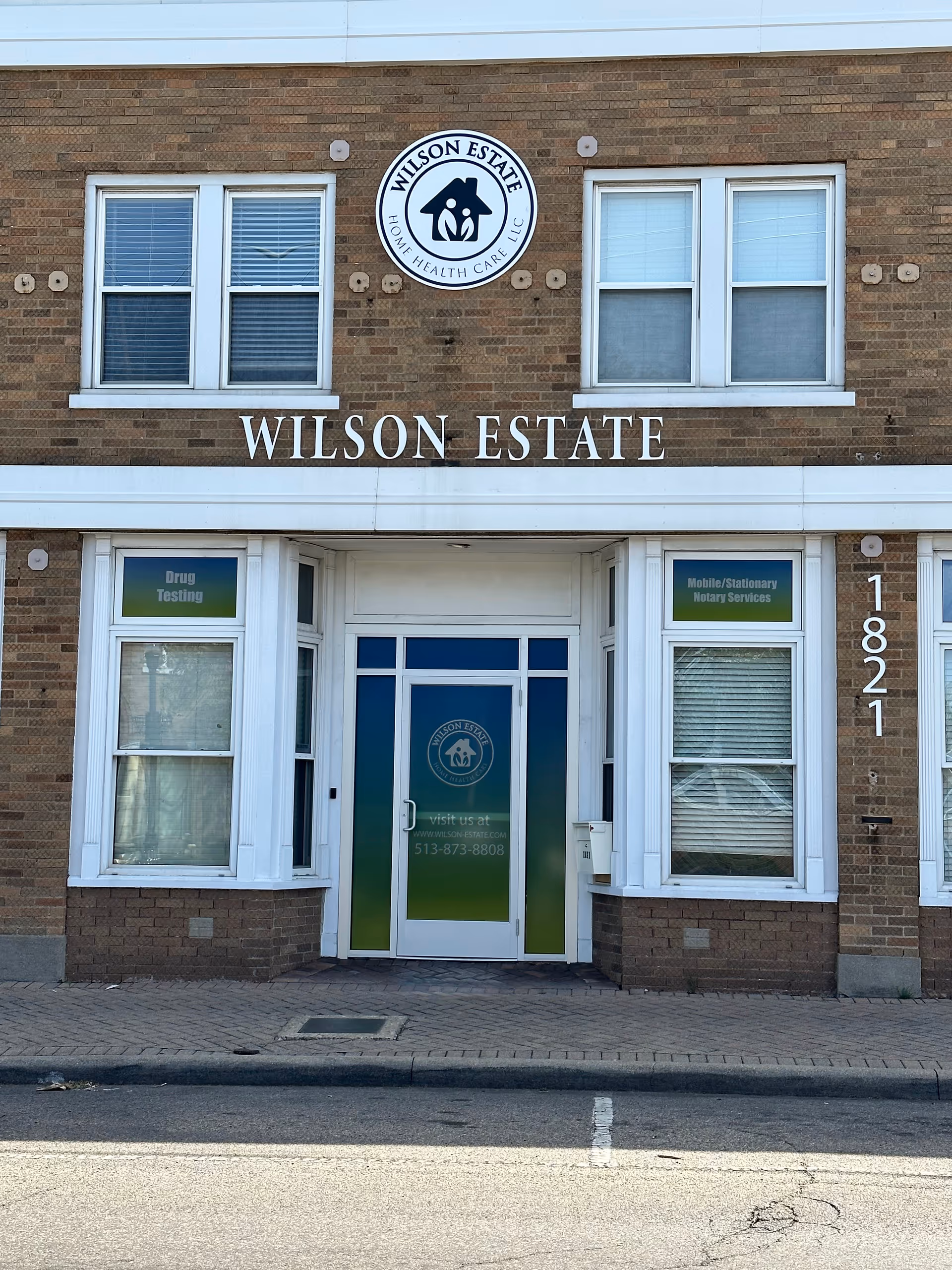 Exterior brick facade of Wilson Estate facility with sign, logo, and entrance doors.