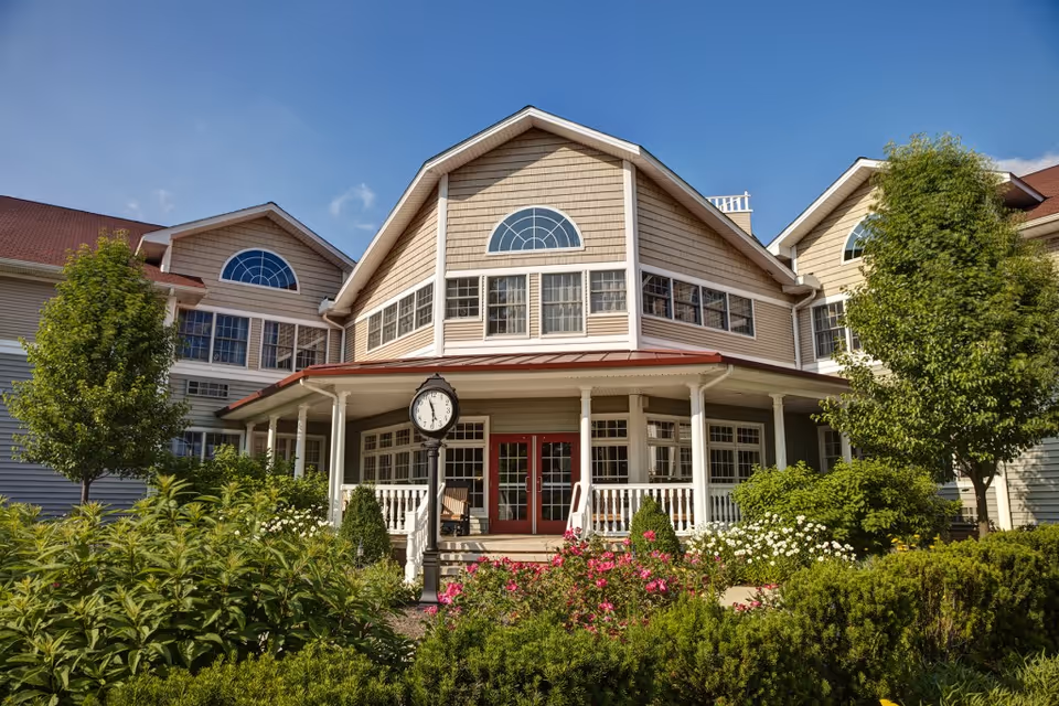 Front view of Briar Hill Health Care Residence with porch, clock, and landscaped garden.