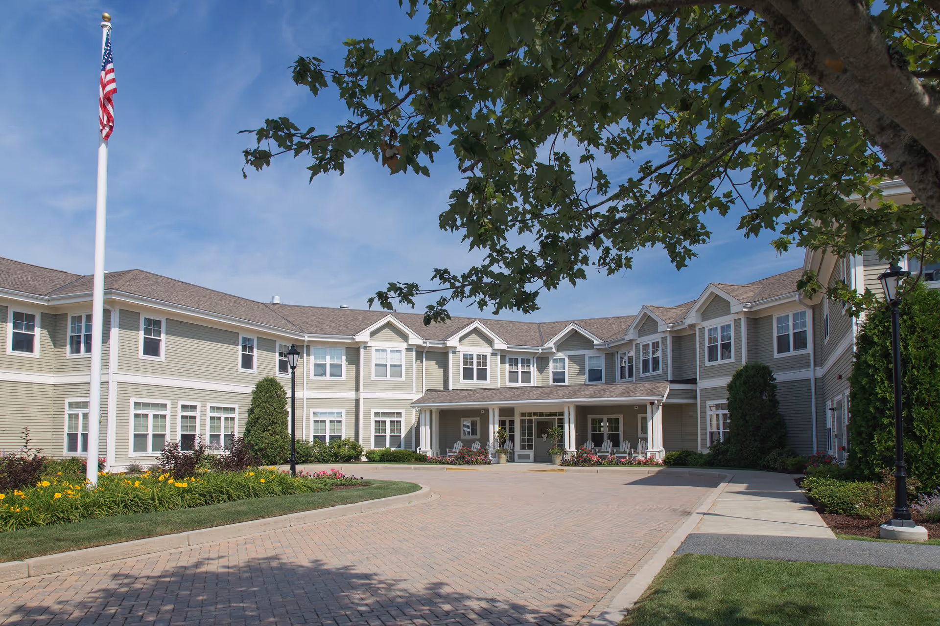 Exterior view of The Residence at Cedar Dell, senior living campus with a flagpole and landscaping.