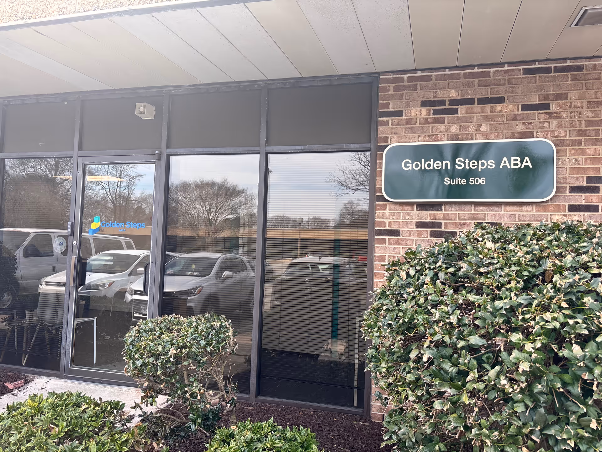 Exterior view of Golden Steps ABA facility with glass entrance and manicured shrubs.