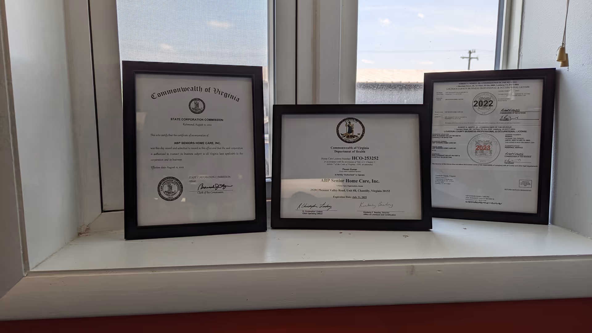 Three framed certificates on a windowsill inside ABP Senior Home Care Inc.