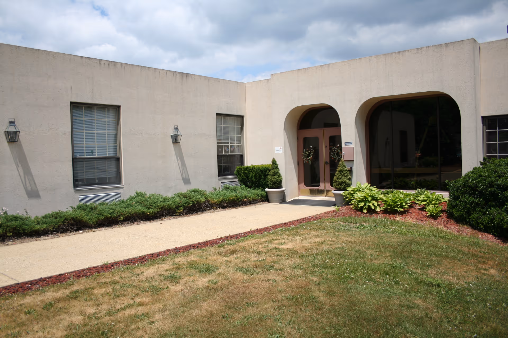 Exterior view of Quality Life Services Sarver building entrance with arches and landscaping