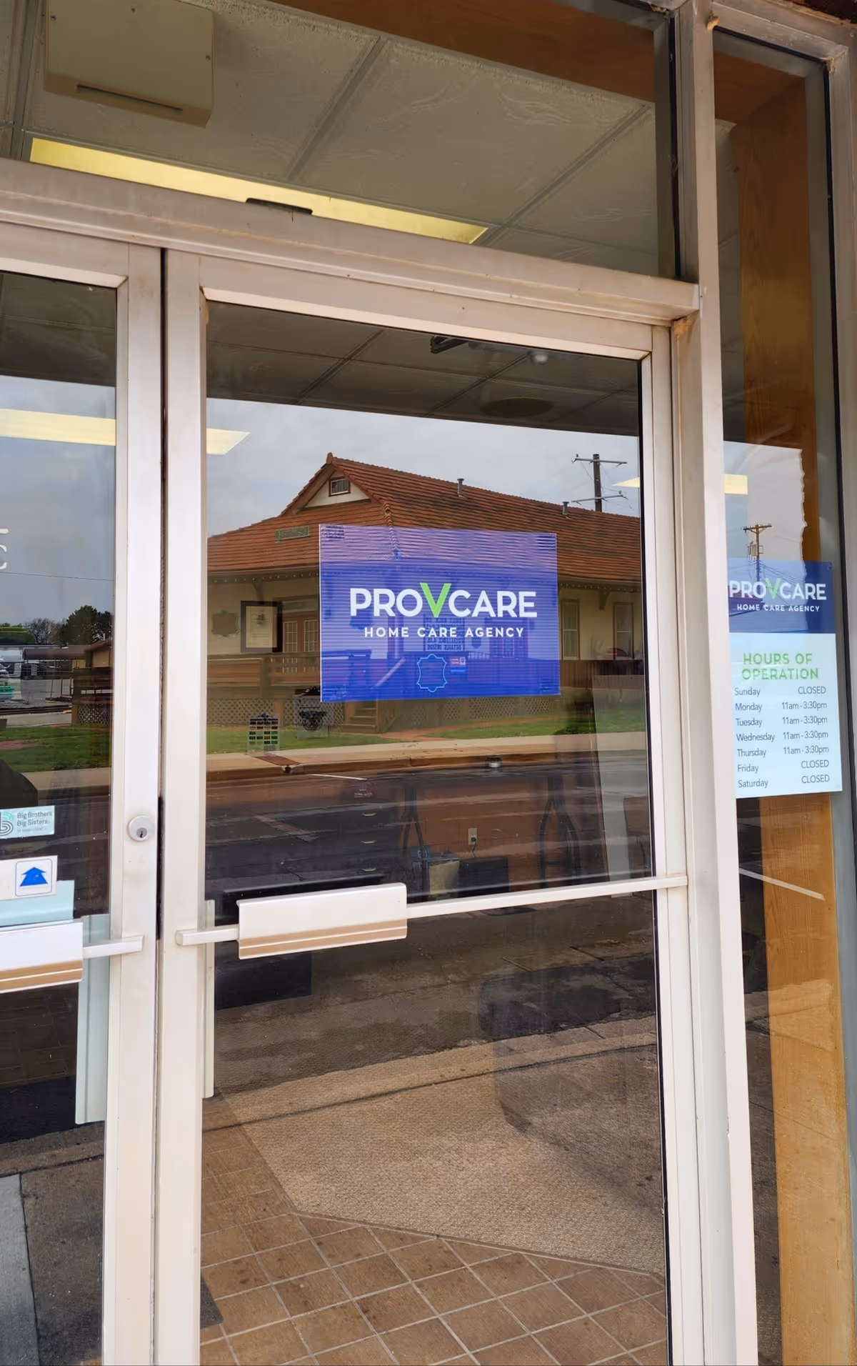 Glass entrance doors display ProVcare sign with hours; exterior street reflection.