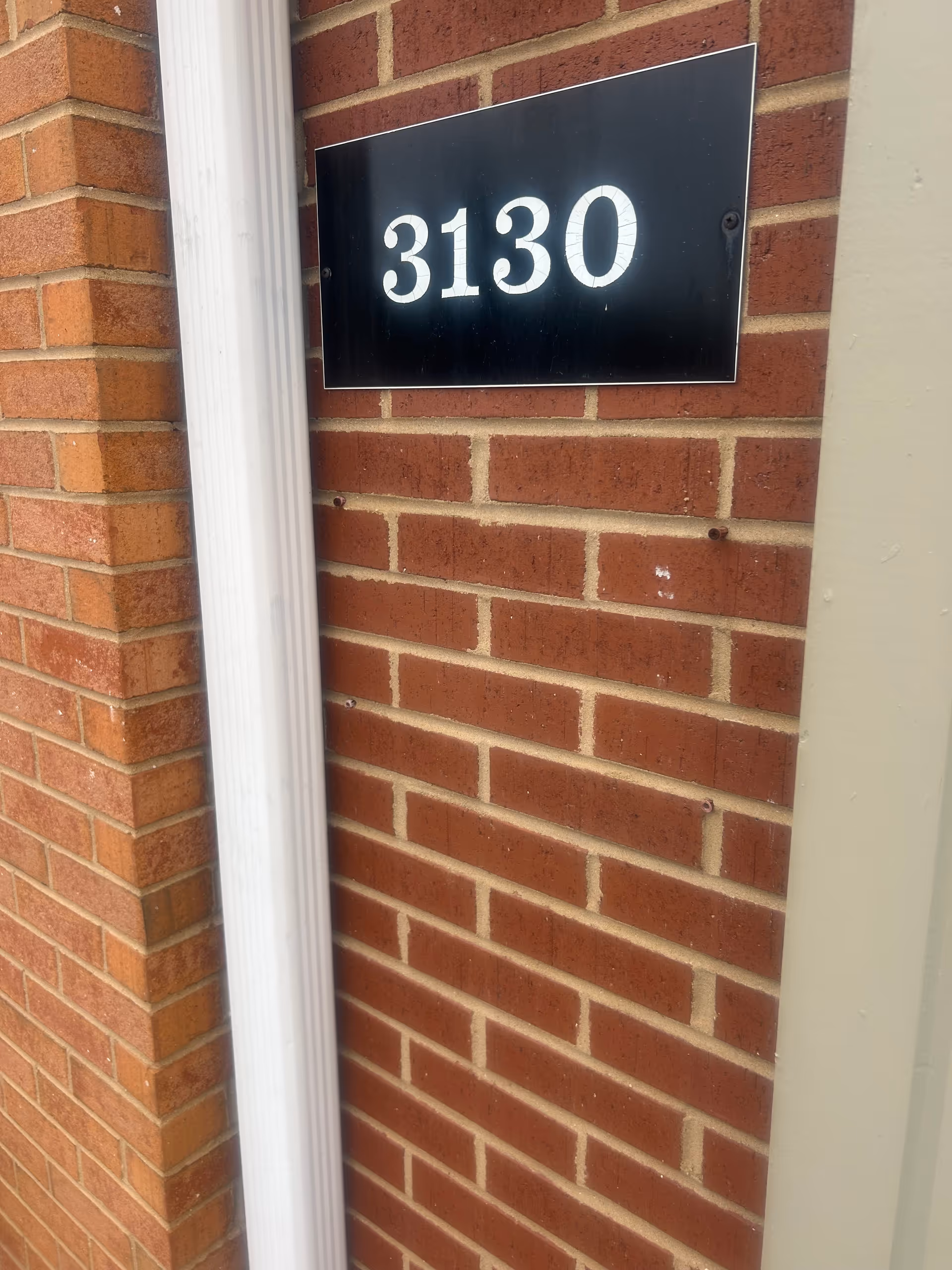 Brick exterior with a black plaque displaying number 3130 on the wall.