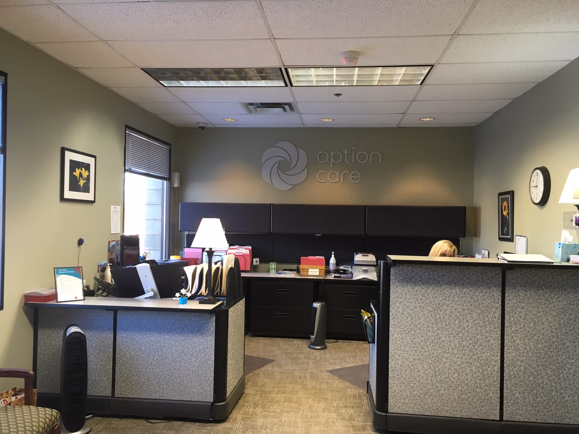 Reception area with desks, computers, and a wall logo reading option care.