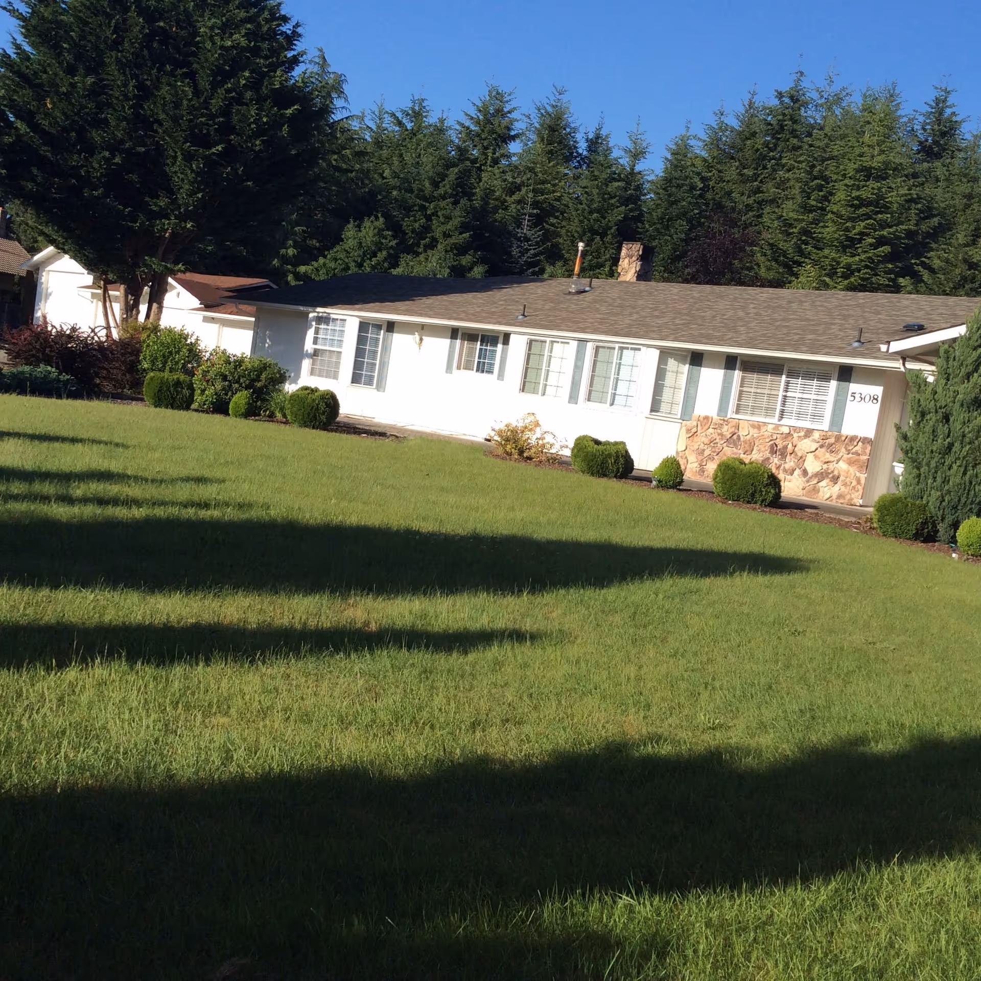 Single-story senior living facility front with green lawn and trees.