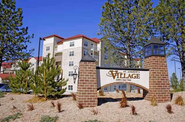 Entrance sign reading 'St. Andrew's Village' in front of a multi-story residential building with trees and landscaped grounds.