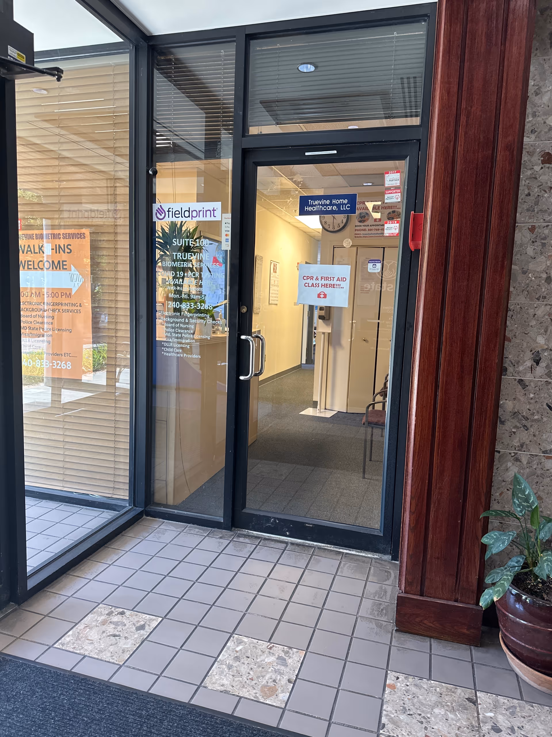 Glass entrance doors of Truevine Home Healthcare Services with posted signs.