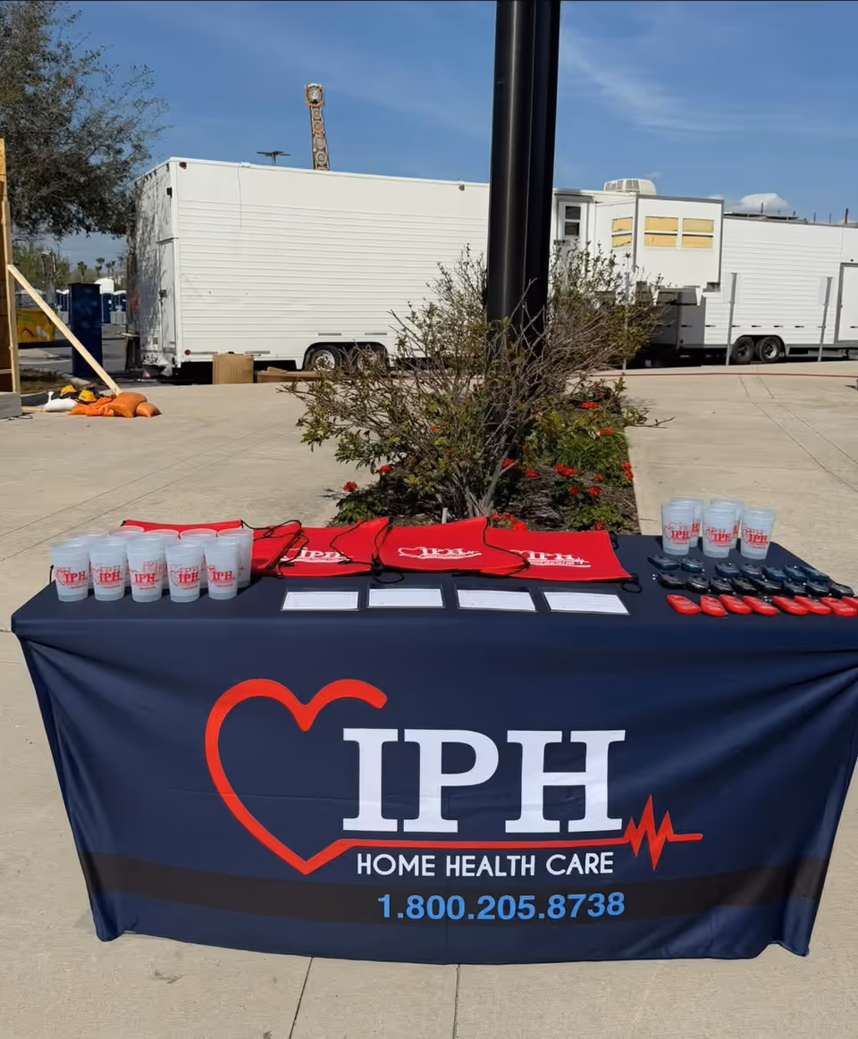 Outdoor IPH Home Health Care table with cups, bags, and flyers